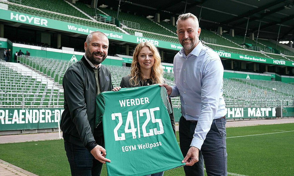 Christian Rauhut, Eva Ihlenfeld und der EGYM Wellpass-Partner halten ein Trikot mit der Vertragslaufzeit.