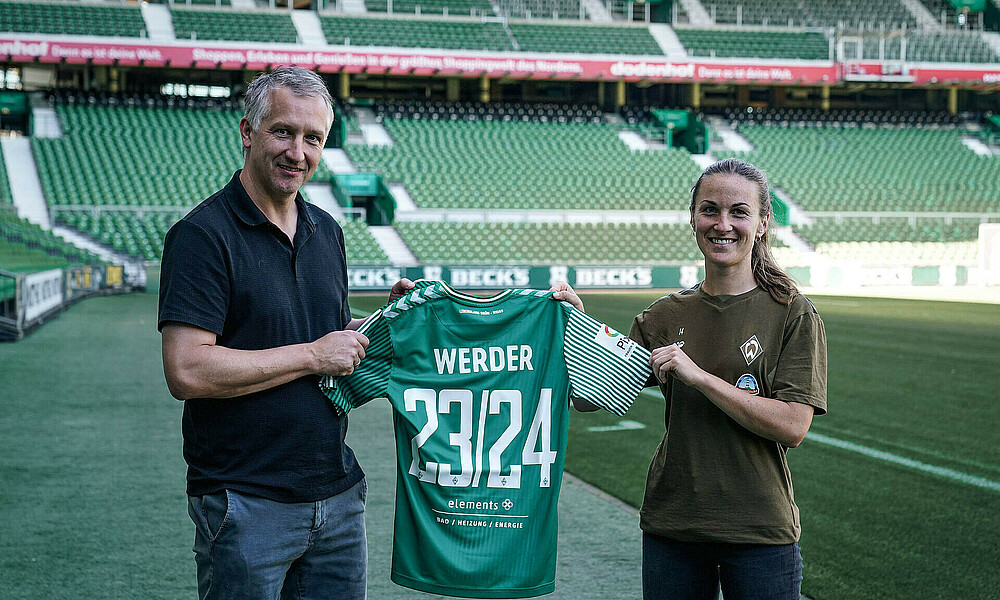 Frank Baumann und Michaela Brandenburg halten ein Trikot mit der Aufschrift ELEMENTS