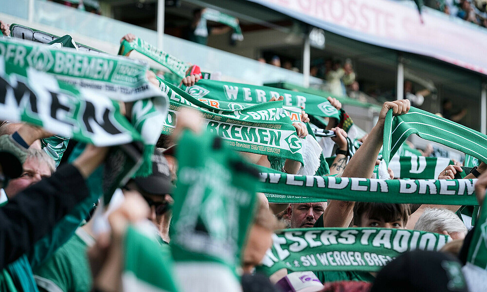 Werder Fans halten ihre Schals hoch.
