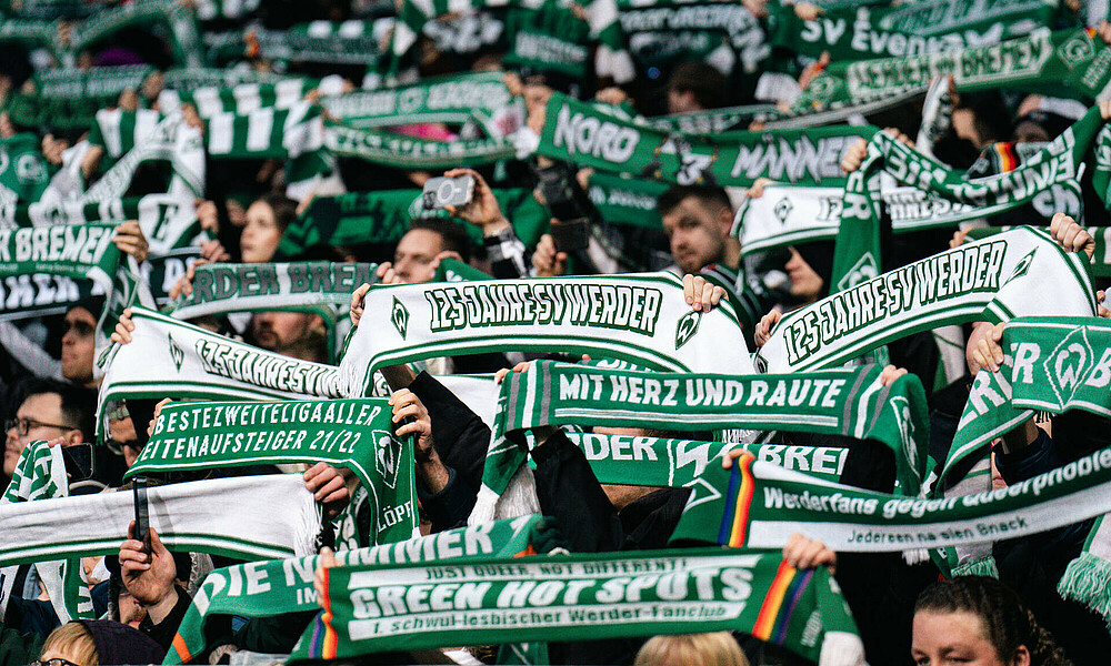 Fans halten ihre Schals hoch.