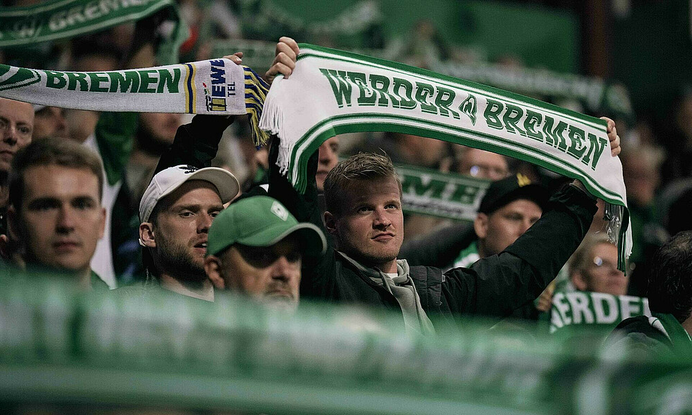 null Ein Fan hebt einen Werder-Schal während des Spiels hoch.