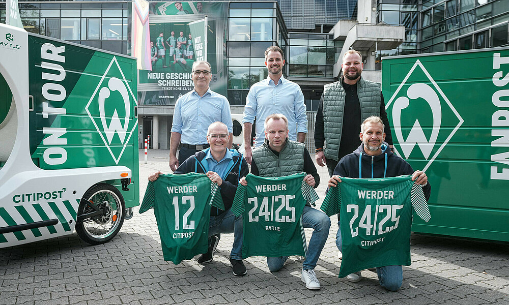 Vertreter von RYTLE und CITIPOST sowie Werder stehen vor dem Stadion mit Trikots in der Hand.