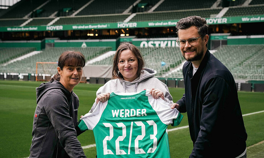 null Eine Vertreterin von CSL Plasma mit einem Werder-Trikot auf dem 22/23 CSL Plasma steht