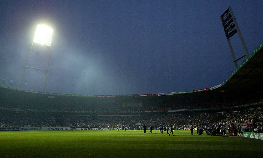 Ein Flutlichtmast scheint auf das sonst dunkle wohninvest WESERSTADION.