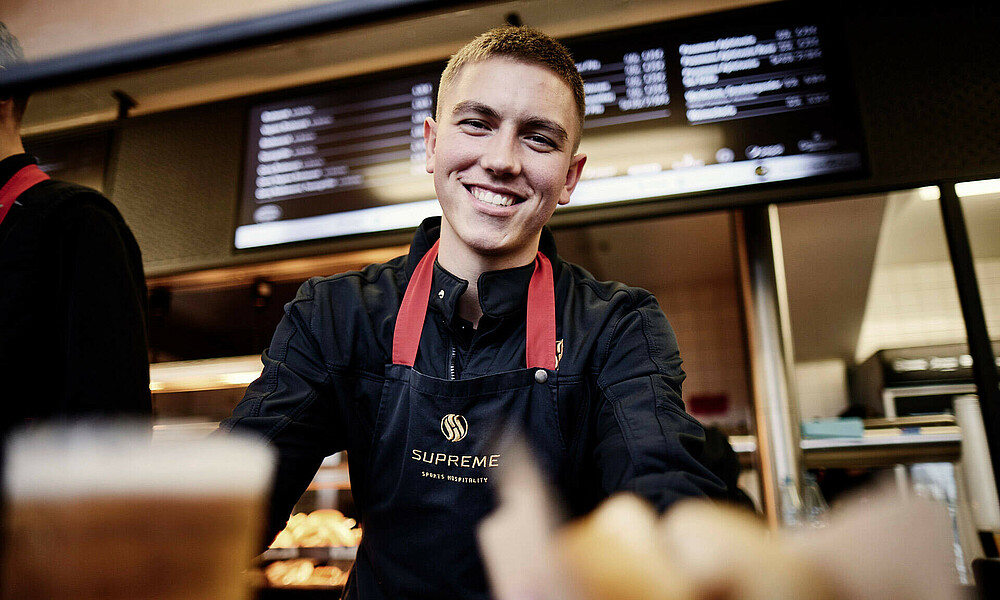 null Ein Mitarbeiter der Supreme Sports Hospitality guckt beim Bedienen in die Kamera.