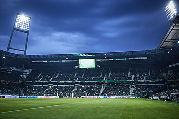 null Blick auf die Ostkurve des wohninvest WESERSTDAION bei einem Flutlichtspiel.