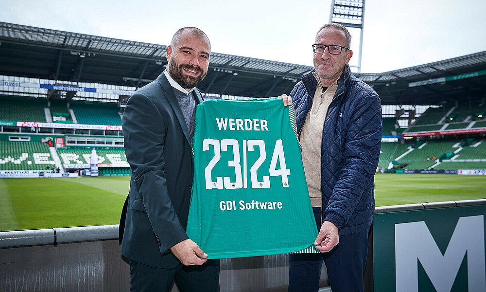 null Christian Rauhut und der Vertragspartner halten ein Trikot mit der Vertragslaufzeit hoch.