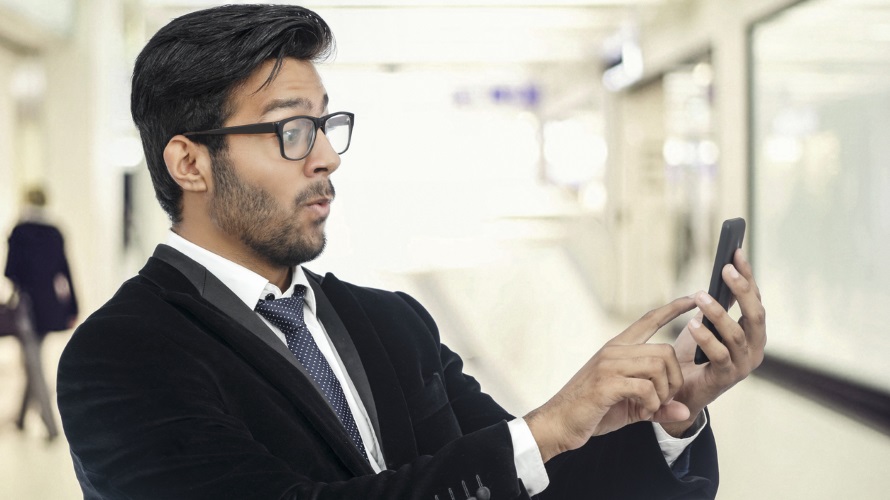 ManGlassesSmartphoneConfused