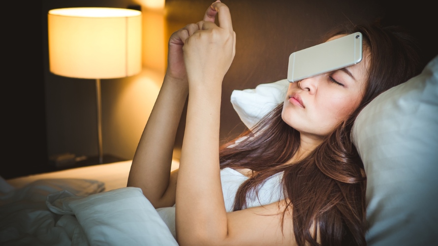 Sleepy asian woman in white bed, dropped smart phone on face
