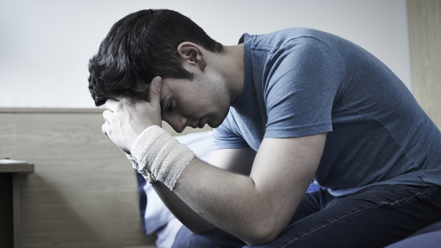 Depressed Young Man With Bandaged Wrists After Suicide Attempt