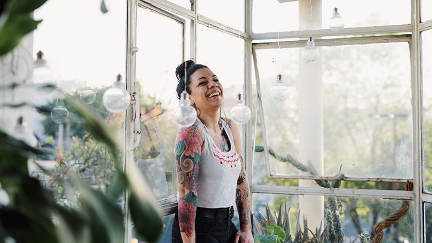 connect-latino-millenials-content-2019 A woman stands near a window laughing with joy