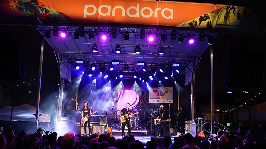 memorable-experiential-activations-sxswcontent-2019 A band plays on stage in front of a packed crowd; on the stage there is a Pandora banner