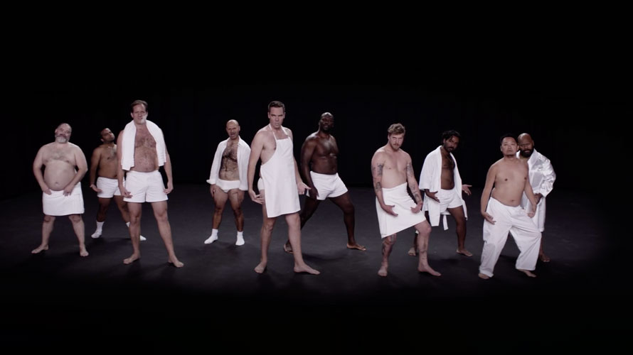 real-audience-fathers-CONTENT-2019 On a dimly lit stage there are numerous men dressed in only aprons