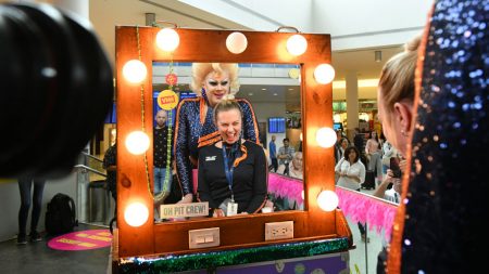 Drag queen and flight attendant in front of a makeup mirror