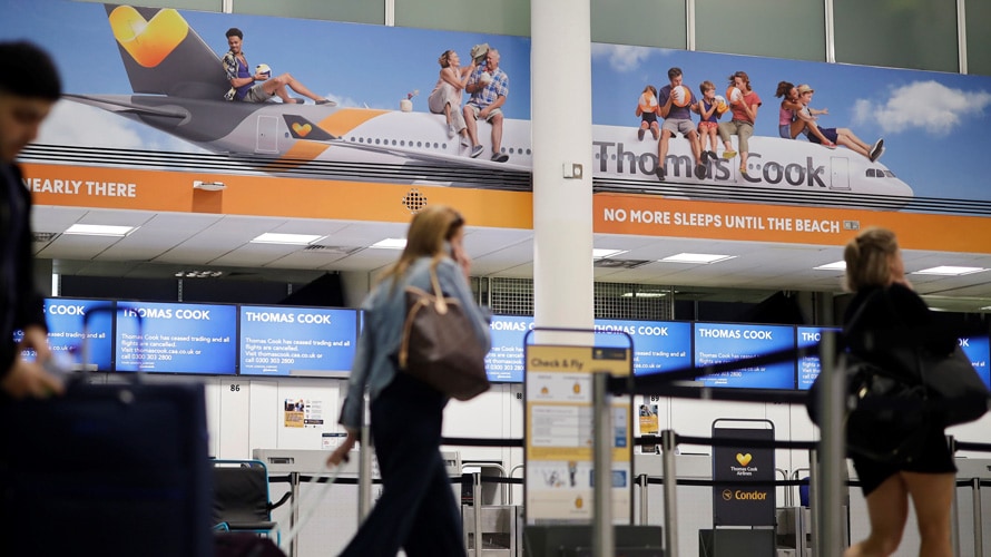 thomas-cook-gatwick-CONTENT-2019 A traveler walks past Thomas Cook signage in an airport.