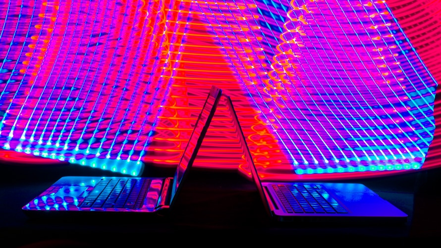 streaming-war-services-CONTENT-2019 opened laptops back to back with neon lights in the background
