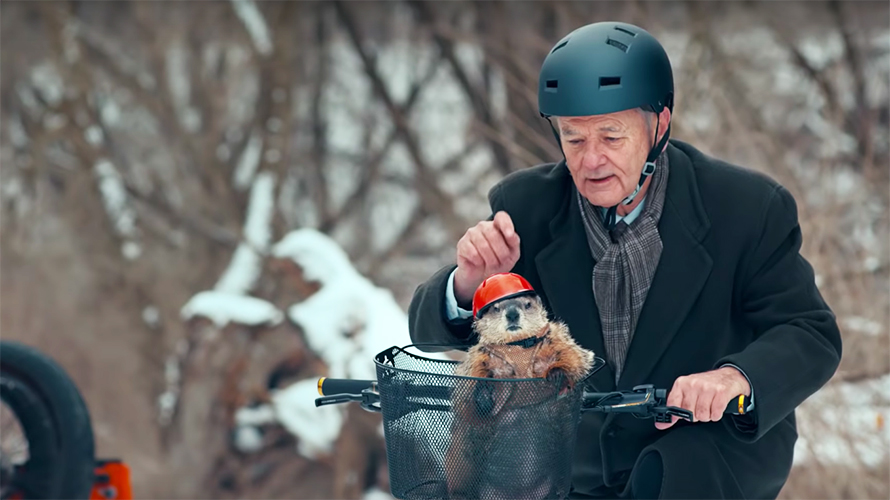 super-bowl-bot-versions-of-ads-bill-murray-2020 Bill Murray wears a bike helmet and rides a bike with a helmet-wearing groundhog in the basket