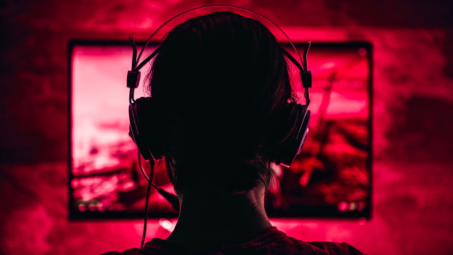 Woman wearing headphones playing video games late at night