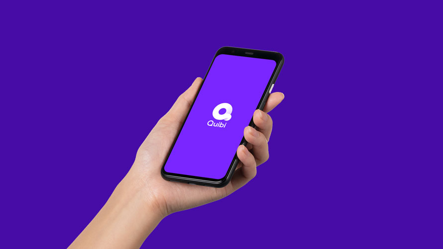 quibi-downloads-CONTENT-2020 Photo of a purple background with a hand holding a smartphone with the Quibi logo