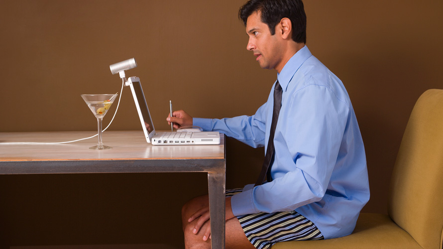 video-personal-business-harm-CONTENT-2020 a man sitting at a desk in his underpants with a button-down shirt on and a martini next to his laptop