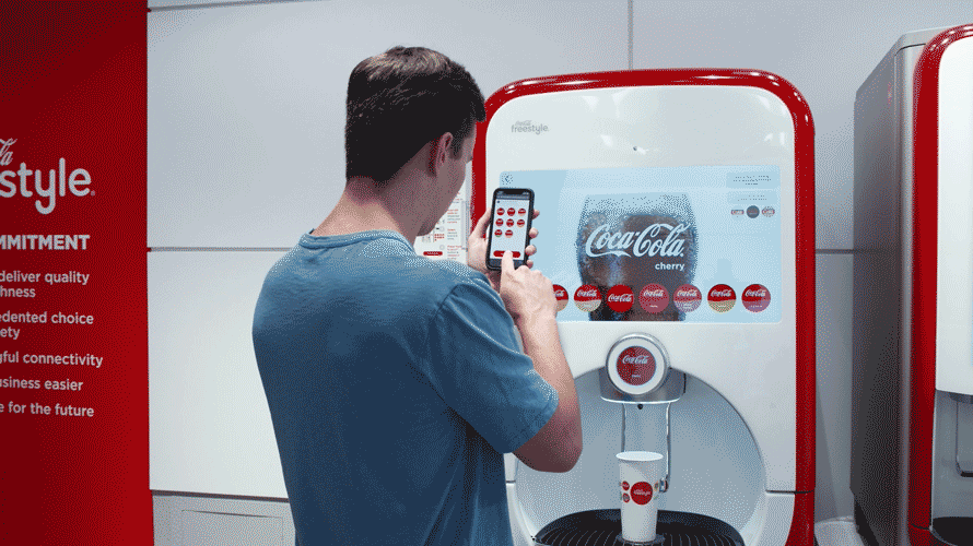 coke-touchless-vending-maching-CONTENT-2020 a man using his phone to select a coke from a coke vending machine