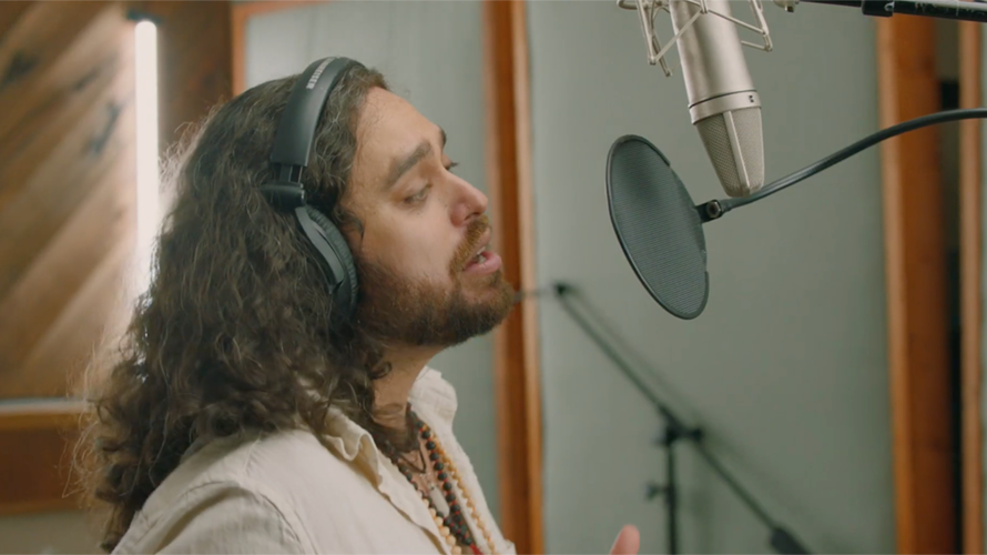 merryfield-hed-content-2020 a man with longer hair crooning into a microphone
