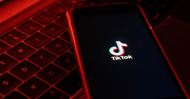 marketers-learn-tiktok-dating-2021 Photo of cell phone loading TikTok app in red light,
