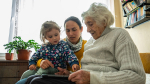 older woman looking at tablet next to a woman and child