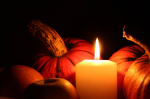 lit candle next to pumpkins 