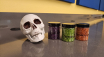 a skull and three small jars of colored beads on a table