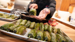 a cook showing off a tray of seasoned peppers in a kitchen