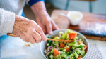 an older person scooping a salad