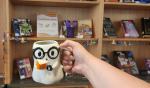 a ghost shaped mug held in front of a Halloween book display