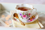 floral teacup of tea on a saucer with a gold spoon