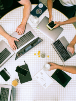bird's eye view of table with laptops and a few peoples' hands holding devices
