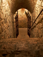 sand-colored stone walls leading down stairs to iron gate