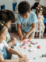 Kids playing and making art together on a table.