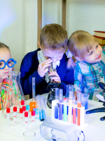 Happy children crowded around science materials.