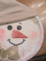 cheerful snowman face painted on round pizza pan