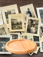 A pile of old black and white photos with a wooden drink coaster in front of them.
