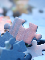 Puzzle pieces in shades of light blue and pink are set against a soft background.
