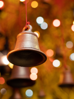 A golden bell features in the foreground while multicolored lights glow softly in the background.