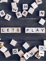 Wooden scrabble tiles against a dark background spell out the words "Let's play".