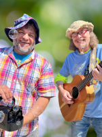 Two entertainers hold fun props and smile at the camera: a guitar and a bubble machine.