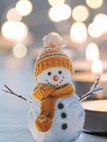 Tealight candles softly glow against a muted background; a snowman with a knitted yellow hat smiles 
