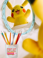 Pikachu, a character from the children's franchise Pokemon, peers happily into a teal vanity mirror.