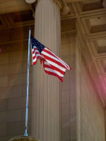 American flag flying in front of Capitol columns