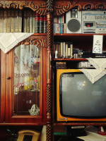 An assortment of old technology and books on an antique bookshelf.