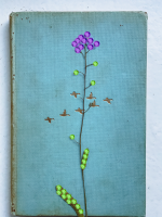 A blue book cover featuring a purple flower and golden birds. The purple flower and green leaves are