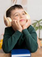 A child wearing headphones sitting at a table with a blue book on it.